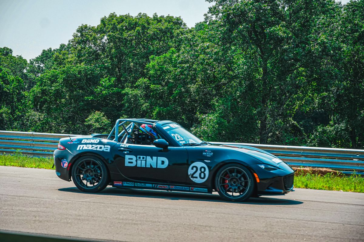 Side view of a Black Mazda racecar on the OIR track