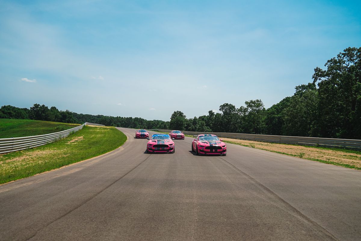 Four pink racecars driving towards the camera on the OIR race track